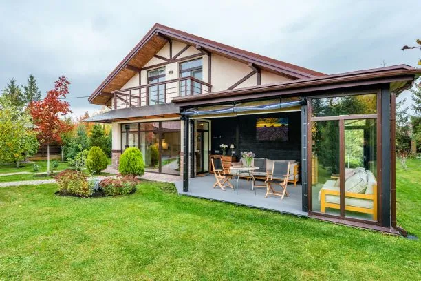 A beautiful modern house with a spacious garden and a cozy, enclosed patio featuring wooden chairs and a table, perfect for outdoor dining and relaxation."
